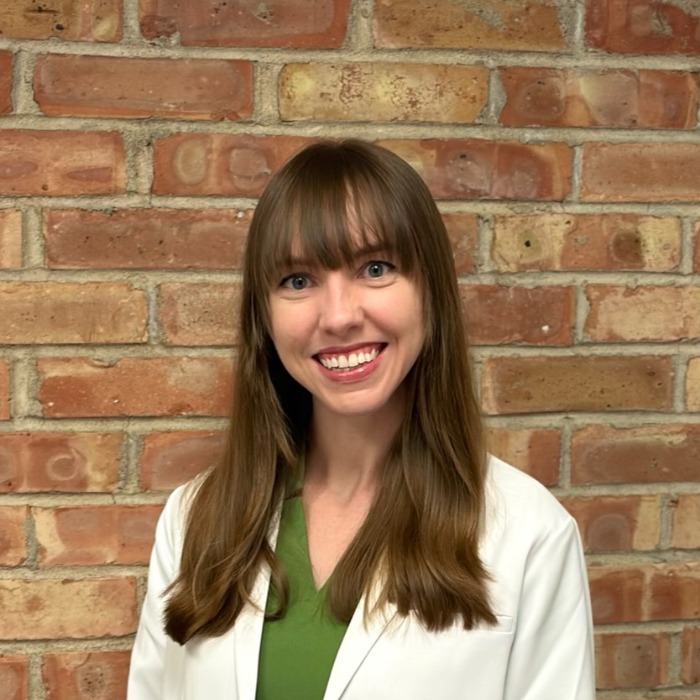 Christine Barnes professional headshot female practitioner in green scrubs with white lab coat